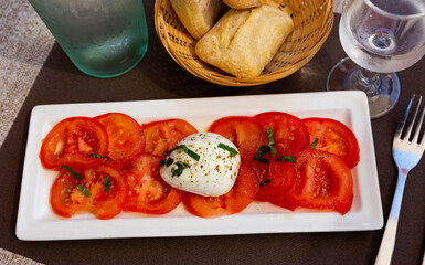 Plate of fresh tomatoes and Mozzarella with greens – Italian caprese