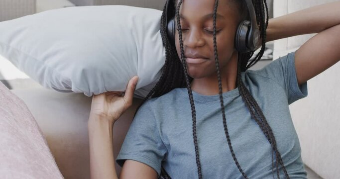 Happy african american teenage girl wearing headphones listening to music
