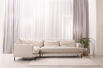 Comfortable sofa and window with beautiful curtains in room. Interior design