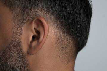 Fototapeta premium Man on light grey background, closeup of ear
