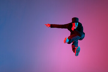 young guy dancer jumps and in flight shows his hand to the side to empty place, hip hop performer advertises