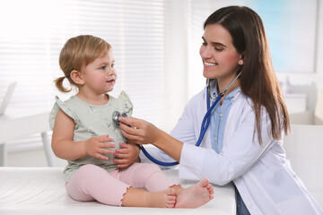 Pediatrician examining baby with stethoscope in clinic - obrazy, fototapety, plakaty