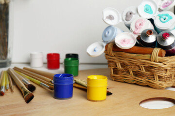 Artist's palette, colorful paints and brushes on white wooden table