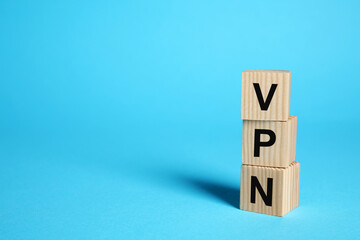 Wooden cubes with acronym VPN on light blue background, space for text