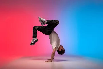 Fotobehang young guy dancer is dancing break in neon lighting, male acrobat is doing trick and dance exercise © Богдан Маліцький