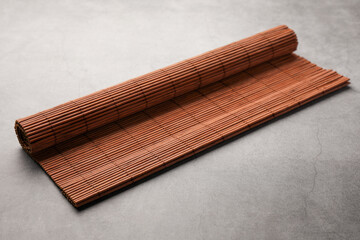 Rolled bamboo mat on grey table, closeup