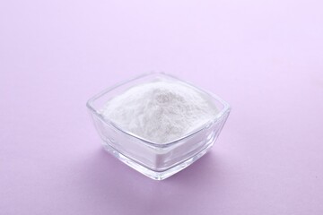 Obraz na płótnie Canvas Bowl of sweet powdered fructose on light purple background