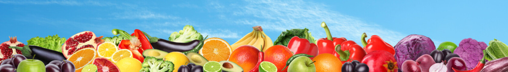 Many different fresh fruits and vegetables against blue sky with clouds. Banner design