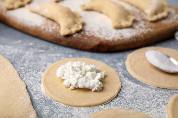 Process of making dumplings (varenyky) with cottage cheese. Raw dough and ingredients on grey...