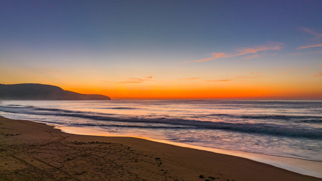 Soft hazy sunrise seascape and vibrant crepuscular rays on the horizon