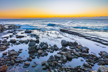 Sunrise over the sea and rocky Inlet with clear skies and a low cloudbank