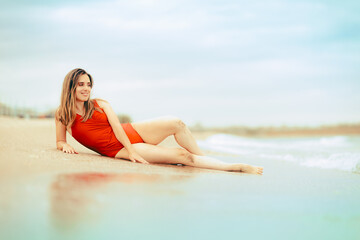 Happy Woman in Red Bathing Suit Relaxing on a Beach. Carefree girl having fun on a summer vacation tropical trip
