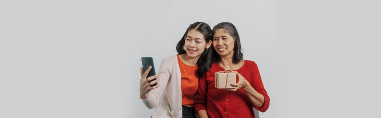 Senior mature asian woman with young daughter sitting together on couch, giving hug and love feeling happy, Mother day, birthday, family anniversary, love mom concept.