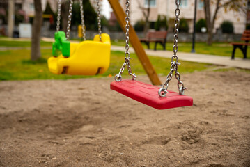  empty children's red swing, children's playground in the city , children's entertainment area with play sand floor ,