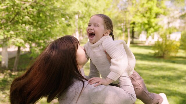 happy family. mom hugs child girl daughter park. cheerful girl spinning her mother arms. happy child. child dream mom. kid laughs his mother arms park. happy family concept. child runs green grass