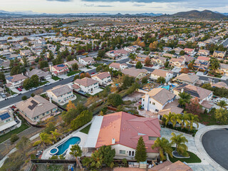 Obraz premium Aerial view of home with pool on a cul de sac street surrounded by luxury single family homes rolling hills in new residential West Coast USA real estate suburban neighborhood dramatic sunset sky