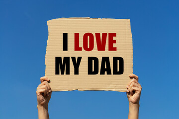 I love my dad text on box paper held by 2 hands with isolated blue sky background. This message board can be used as business concept about loving father.