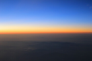 Amazing view from plane on the orange sky, sunset sun and clouds.