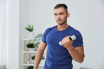 Man sportsman training at home with dumbbells, exercises for arms and back muscles, strong body and...