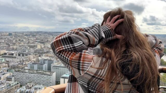 A girl on a eiffel tower looks around at the city of Paris visible houses the Seine River with boats and the city 06.04.22 Paris France center. High quality 4k footage