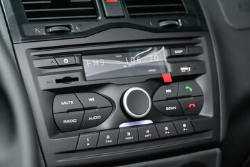 A close up on a black panel with radio,  player and control buttons