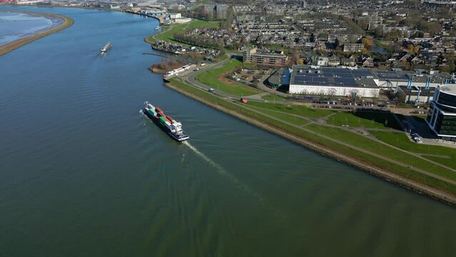Aerial view of bulk contaner ship navigating through the city canal of Zwijndrecht.