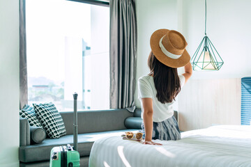 Carefree young Asian traveler female relax on bed in hotel room. Travel alone, summer, vacation concept. Copy space