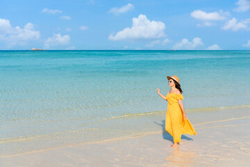Fototapeta na wymiar Beautiful young Asian woman relax smile walking around sea beach ocean with white cloud on blue sky in travel vacation. Copy space