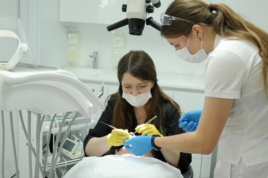 the doctor and the nurse bent over the patient, they treat the teeth, they fill the canals Close-up medical dentist procedure of teeth cleaning. High quality photo