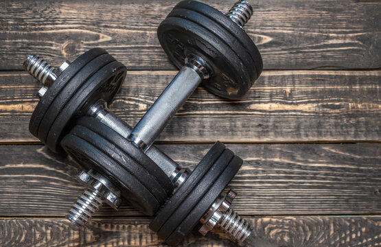 Iron dumbbells with metal pancakes on a wooden background.