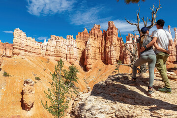 Couple hugging next to old tree Bristlecone Pine. Scenic view of pinnacles on Peekaboo hiking...