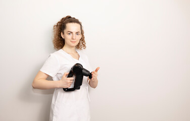 Rehabilitation Specialist, Physical Therapist In White Medical Clothes Holds Massage Gun, Massager Product, Copy Space For Text. Health Specialist, Rehabilitation. Horizontal plane