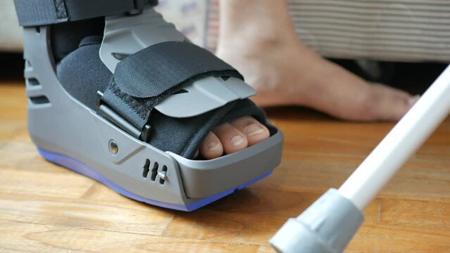 women broken feet with a grey plastic boot ankle brace injury protecting boot