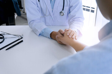 Doctor holding patient's hand, and reassuring his male patient helping hand concept.