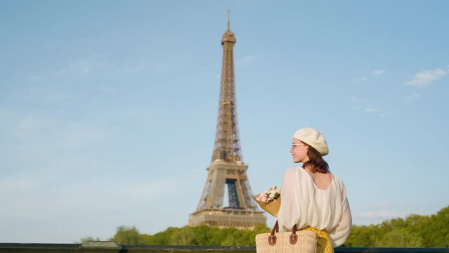 Young female with a bouquet of flowers near the Eiffel Tower at sunset