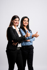 Two young indian business woman or employee showing thumps up on white background.