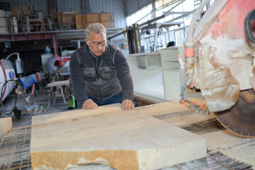 enior carpenter varnishing wood in workshop
