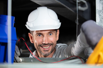 electrician using multimeter in roof space