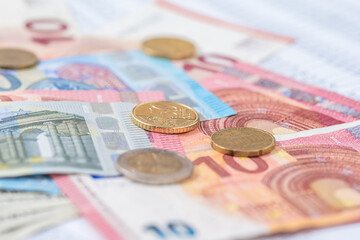 Many Euro banknotes and coins stacked on top of each other.