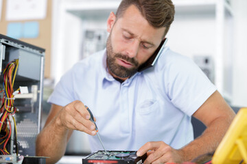 man fixing a pc while talking to customer