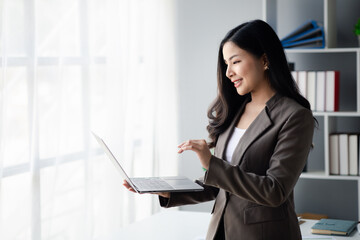Business woman looking at data on laptop, young Asian women as executives, founding and running start-up executives, young female business leaders. Startup business concept.