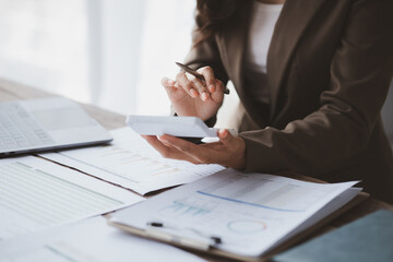 Businessman using a calculator to calculate numbers on a company's financial documents, she is analyzing historical financial data to plan how to grow the company. Financial concept.