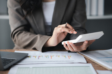 Businessman using a calculator to calculate numbers on a company's financial documents, she is analyzing historical financial data to plan how to grow the company. Financial concept.