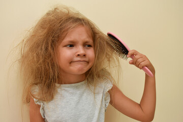 The child tries to comb the thin and very tangled hair with a brush, but it does not work.  Little...