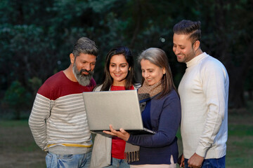 Indian or asian people in warm wear and using laptop at park