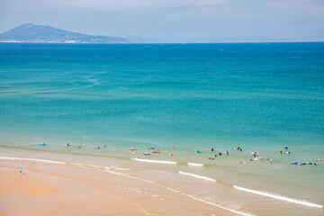 Surfers in the ocean at Cote des Basques beach in Biarritz, France on a summer day - obrazy, fototapety, plakaty