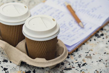 Two paper cups with lid for tea to go. Coffee take away on the table. Take-out coffees with brown paper cup holder. Brown safety cardboard collars. Take away box for cups. Cardboard tray
