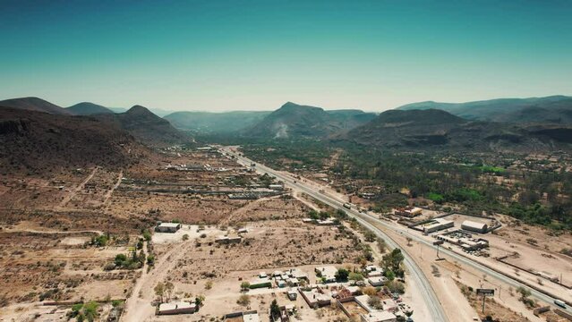 Aerial forward shot of a highway passing through a valley and from the center of a small town, countryside near Queretaro, Mexico - Sandia Mountains Albuquerque New Mexico