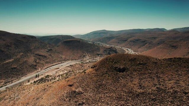 Aerial wide-angle drone shot of the orange-crusted mountains and highway passing through the valley near Queretaro, Mexico - Sandia Mountains Albuquerque New Mexico