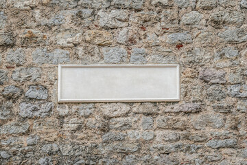 Blank white rectangular plaque on an old stone wall. Template for an inscription. Vintage...